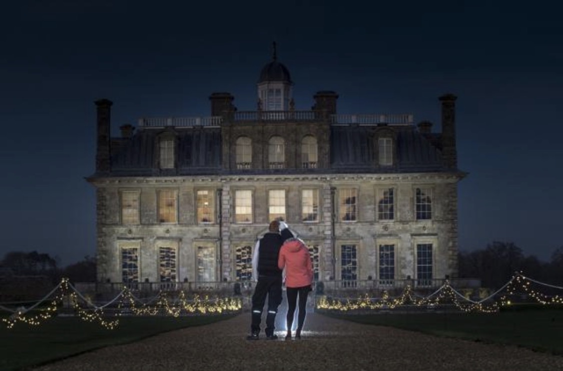 Kingston Lacy's historic house lit up at night, with strings of fairy lights across the lawns